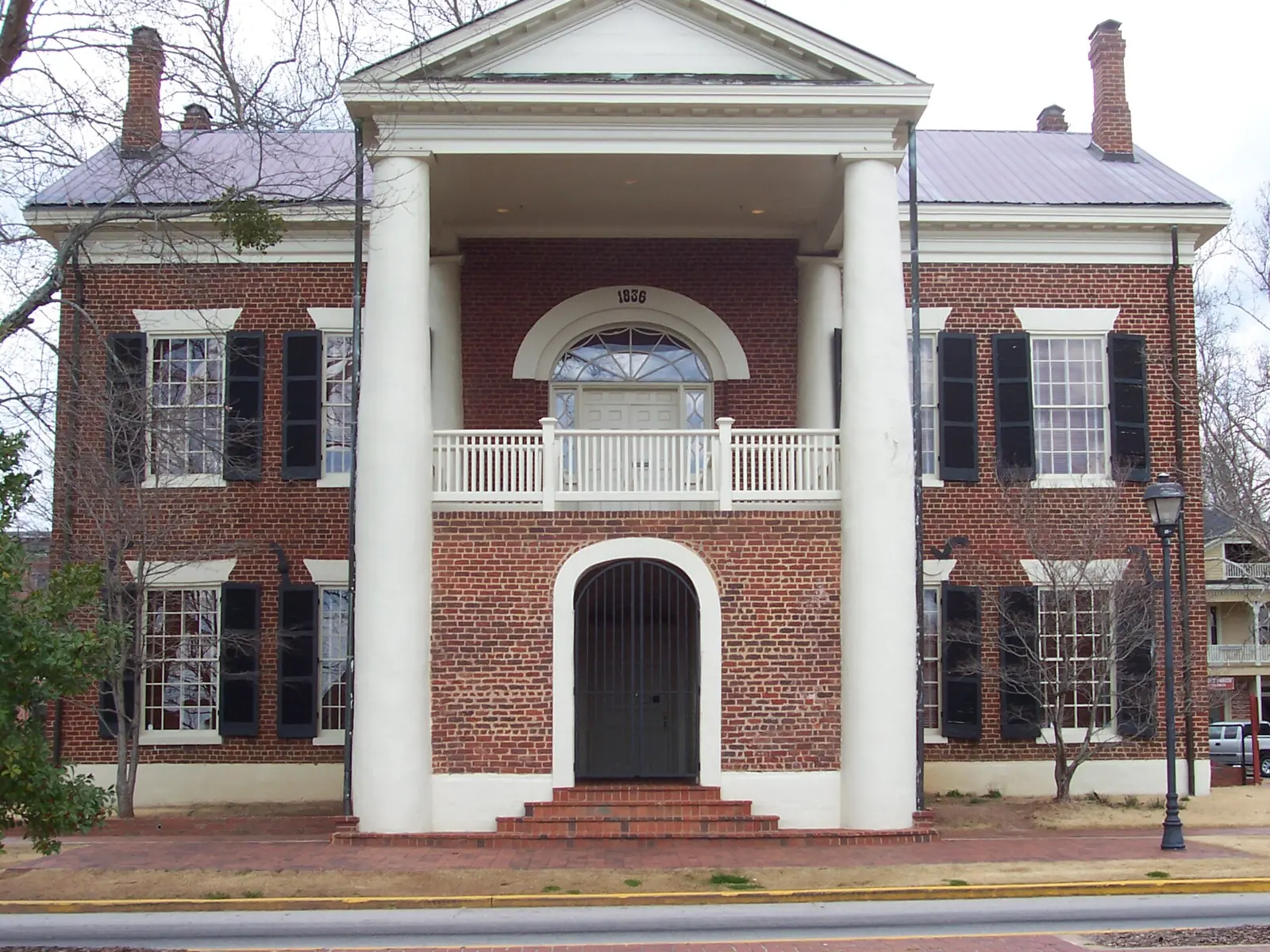Two-storey red-brick 1836 courthouse with white columns, an upper balcony and black shutters, now the Dahlonega Gold Museum